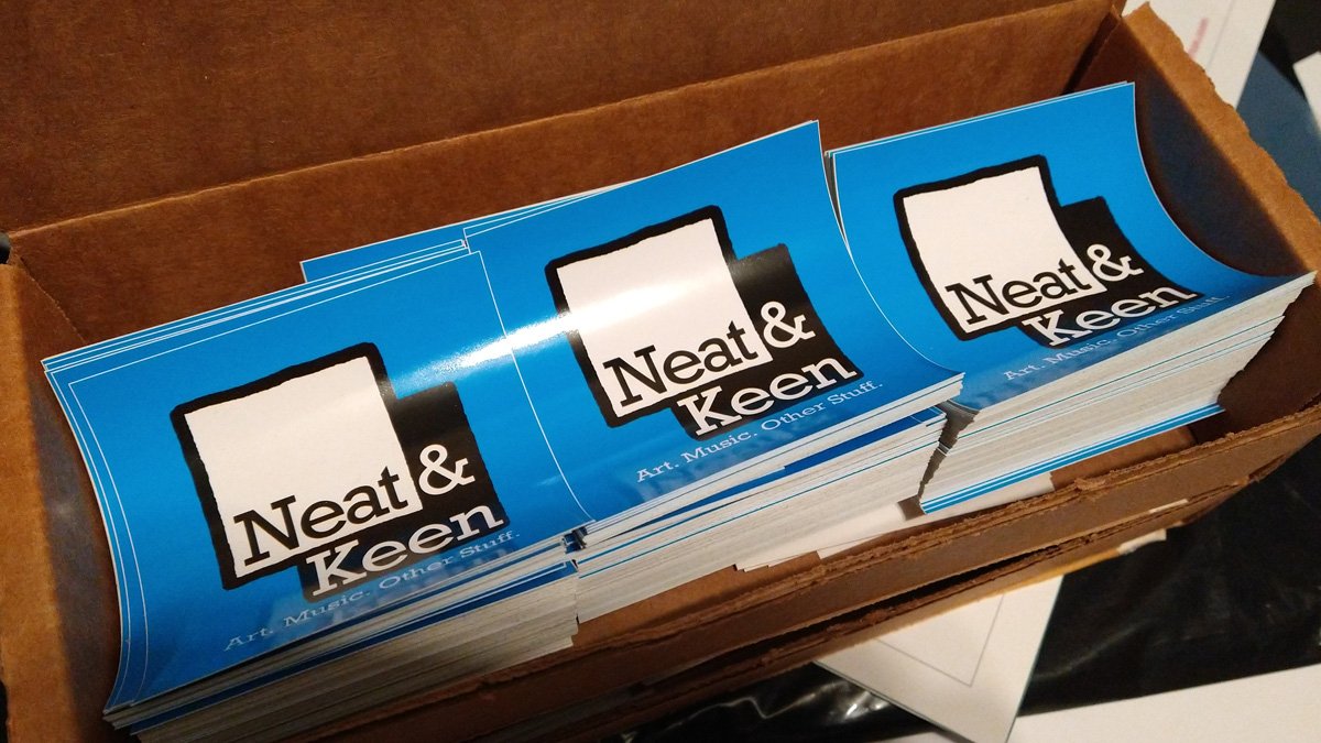 Square stickers in a box bearing the Neat and Keen logo